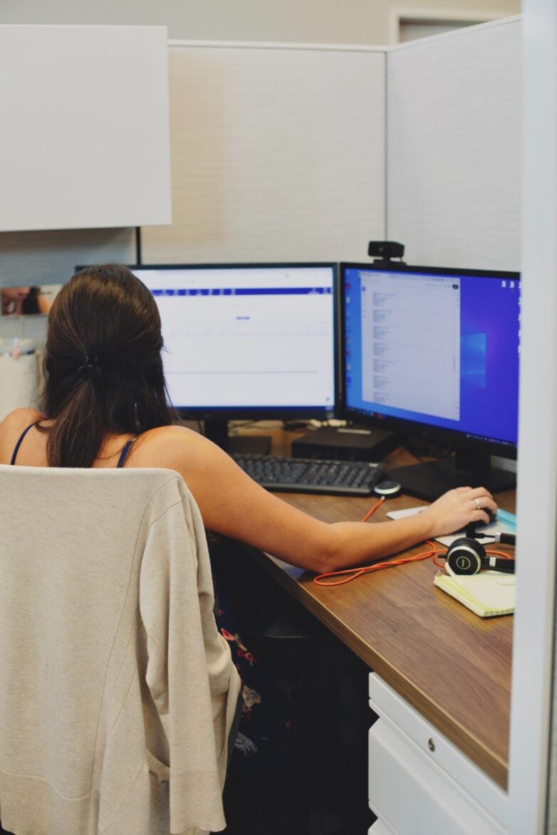 Professional reviewing client figures at a multi-monitor workstation