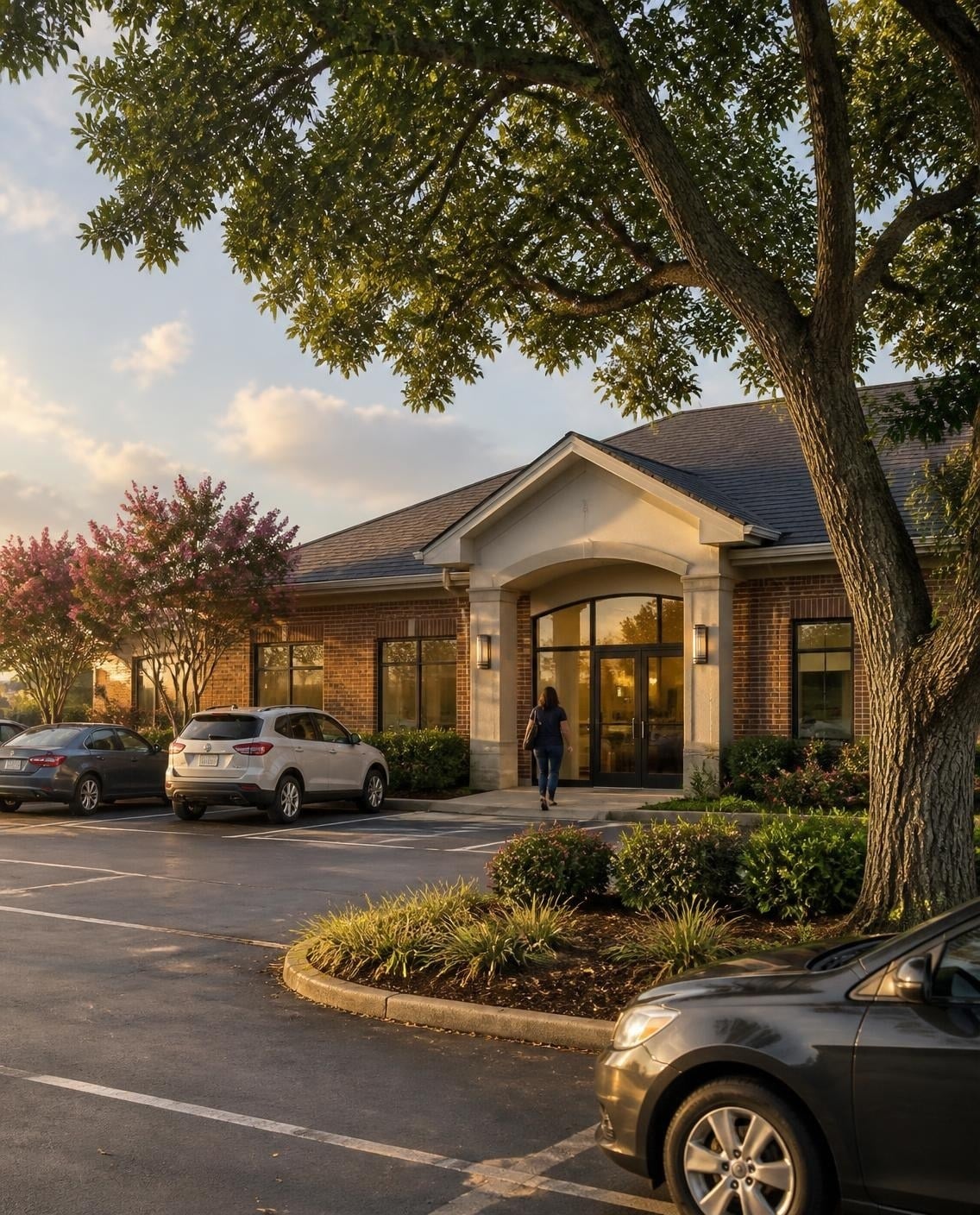 Brick dental office building with crepe myrtles and a live oak at golden hour